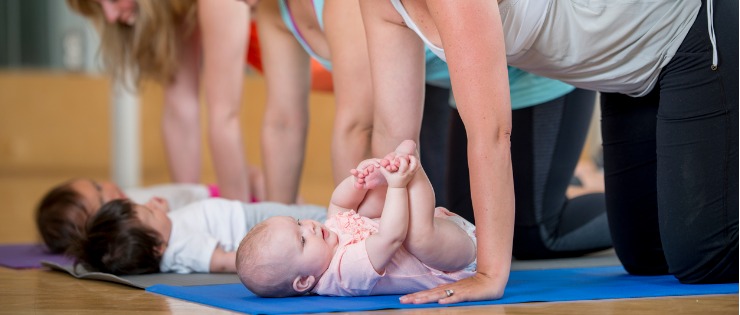 Mums facing their babies on a yoga mat while performing a pose in a Mums and bubs yoga class.