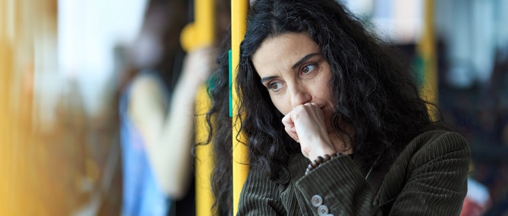 Young woman touching her face on public transport and leaning on bus rail
