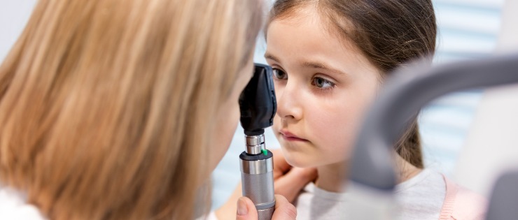 A young girl receiving an eye test from an optometrist.