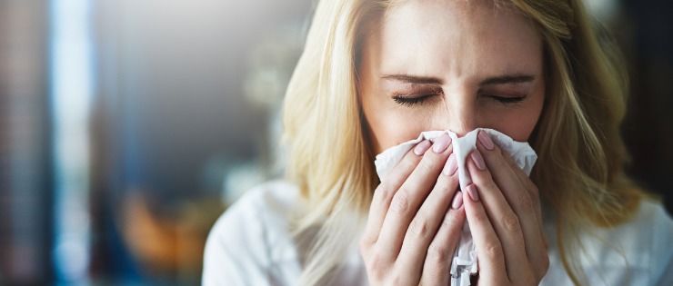Woman suffering from a sinus infection blowing her nose to relieve pressure