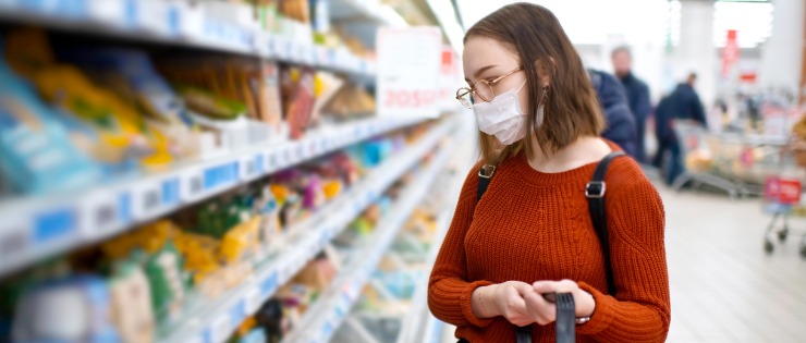 Young female food shopping while wearing a face mask to protect from COVID-19