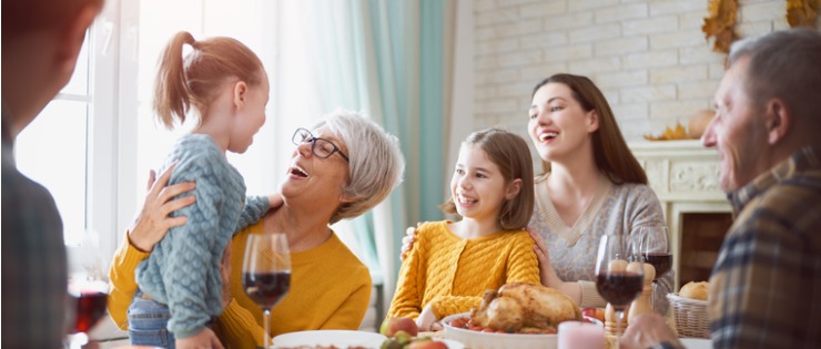 Group shot of a family laughing over dinner having fun with their grandmother