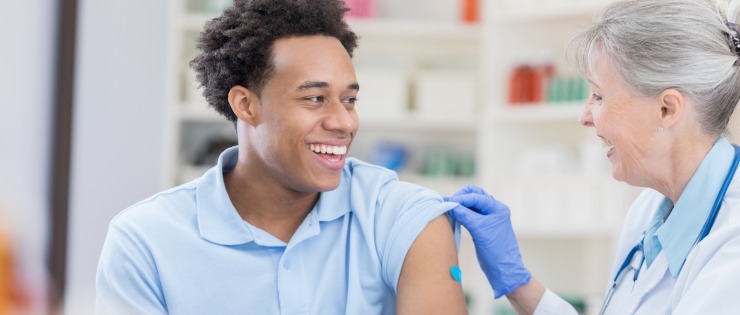 Young man receiving the flu vaccination in his arm by a registered nurse.