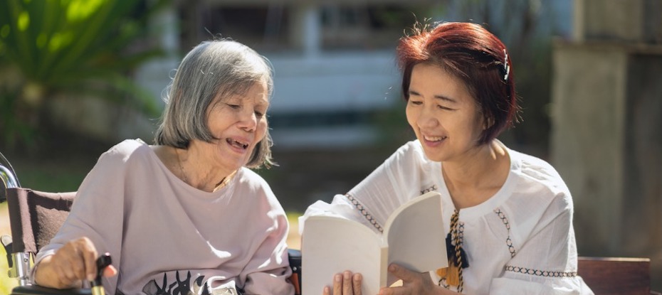 woman caring for her grandmother with dementia by reading a book together