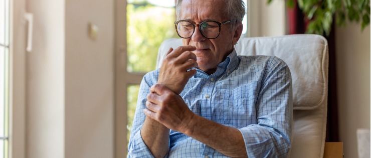 A mature aged man with arthritis holding his wrist after taking a painkiller. 