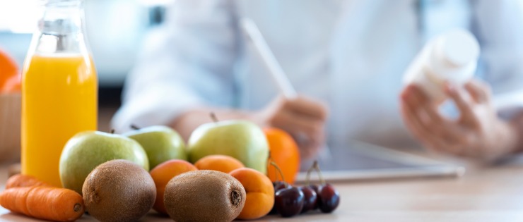 A nutritionist writing out a diet plan with fresh fruit in front of her.