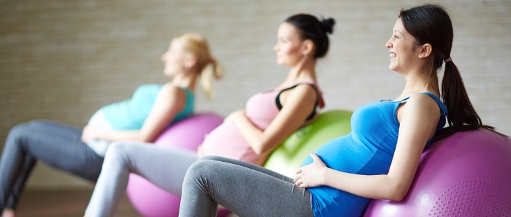 Group of young pregnant mothers exercising at a gym doing a pregnancy safe workout