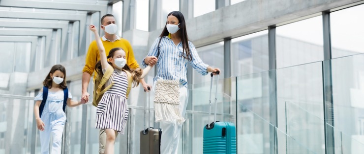 Young family walking through the airport after taking out travel insurance for COVID -19.
