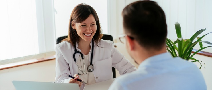 Smiling female doctor talking to man getting his health checked after his holiday