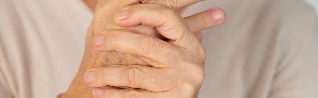 Senior woman massaging her hands together to relieve her chronic pain and discomfort.