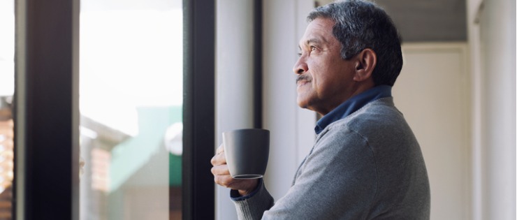 A man standing by the window and drinking tea while thinking about becoming self aware.