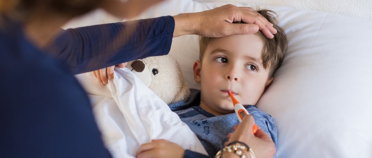 Young toddler sick with the flu, with thermometer in his mouth. 