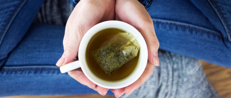 Adult woman pouring herself a cup of green tea 