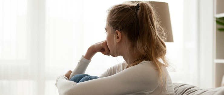 Young female seated on the couch suffering from an anxiety attack