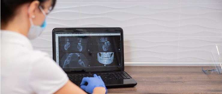 A dental surgeon examining a patient’s x-ray after the information was stored during a teledental appointment
