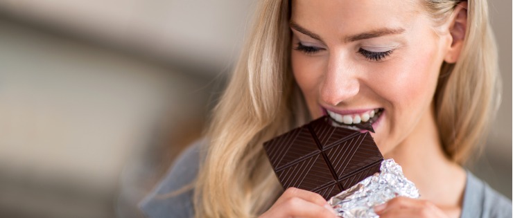 A woman eating dark chocolate for its health benefits