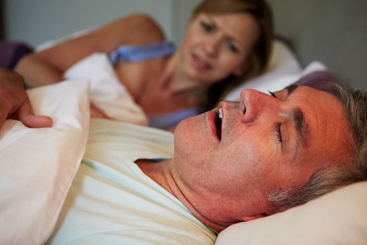 man snoring in bed with wife who is awake